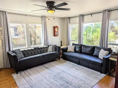a living room with two leather couches and windows at Large 3 Bedroom near everything in San Diego in San Diego