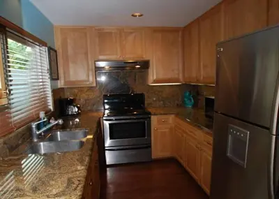 a kitchen with wooden cabinets and a stainless steel refrigerator at Get Your Vitamin Sea! Steps to beach! Fire pit! in Newport Beach