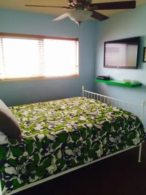 a bedroom with a bed with a green and white blanket at Get Your Vitamin Sea! Steps to beach! Fire pit! in Newport Beach