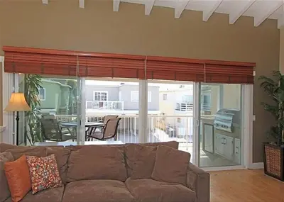 a living room with a brown couch and a balcony at Get Your Vitamin Sea! Steps to Sand, Bikes, & Balcony in Newport Beach