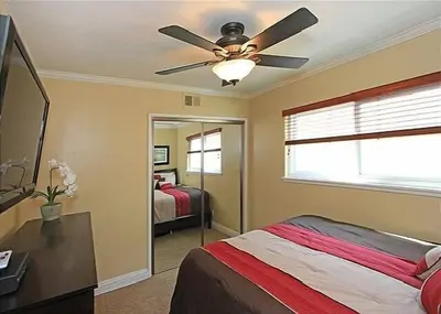a bedroom with a ceiling fan and a bed at Get Your Vitamin Sea! Steps to Sand, Bikes, & Balcony in Newport Beach