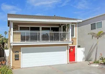 a house with a garage and a balcony at Get Your Vitamin Sea! Steps to Sand, Bikes, & Balcony in Newport Beach