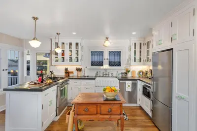 a kitchen with white cabinets and stainless steel appliances at Seahorse Cottage in Secret Garden Sanctuary in San Diego