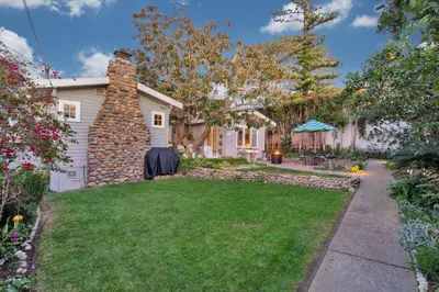 a backyard with a stone chimney and green grass at Seahorse Cottage in Secret Garden Sanctuary in San Diego