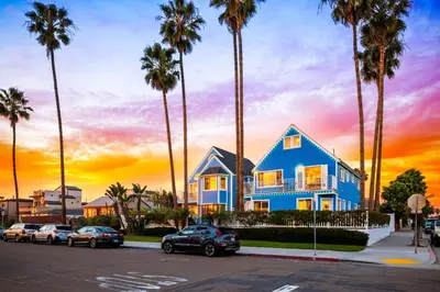 a blue house with palm trees in a parking lot at Huge Beach Views Starfish Cottage Ocean Beach in San Diego