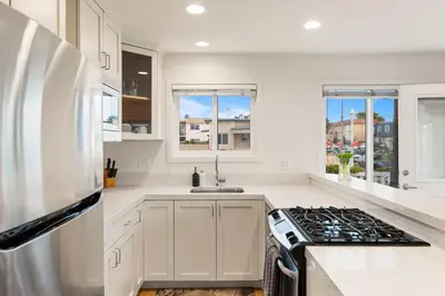 a kitchen with white cabinets and a stove top oven at Ocean Beach Cottage with Views in San Diego