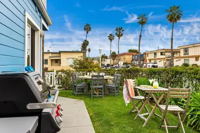 a patio with tables and chairs and palm trees at Ocean Beach Cottage with Views in San Diego