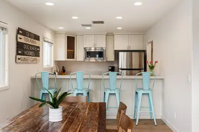 a kitchen with a wooden table and blue stools at OB Cottage Beach Views in San Diego