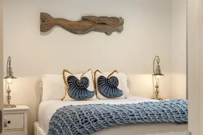 a bed with two blue and white pillows on it at OB Cottage Beach Views in San Diego