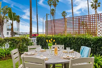 a table with white chairs and a table with yellow flowers at OB Cottage Beach Views in San Diego