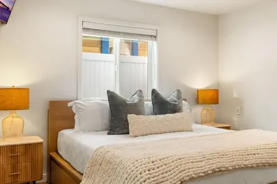 a bedroom with a bed with pillows and a window at OB Cottage Beach Views in San Diego