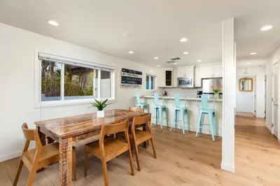 a kitchen and dining room with a wooden table and chairs at OB Cottage Beach Views in San Diego