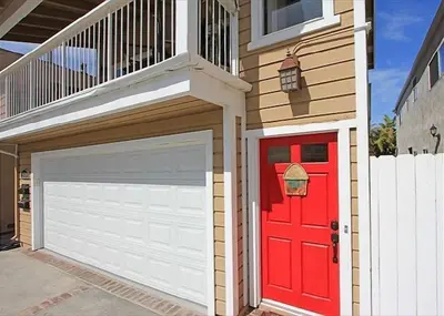 a house with a red door and a garage at 6BR Beach House w/ Bikes/Fire pit/BBQ/Easy Parking in Newport Beach