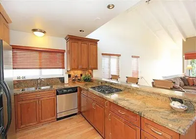 a kitchen with wooden cabinets and a counter top at 6BR Beach House w/ Bikes/Fire pit/BBQ/Easy Parking in Newport Beach