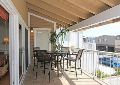 a patio with a table and chairs on a balcony at 6BR Beach House w/ Bikes/Fire pit/BBQ/Easy Parking in Newport Beach