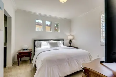 a white bedroom with a large bed and two windows at Walk to Public Transit Oceanside Home with Balcony in Oceanside