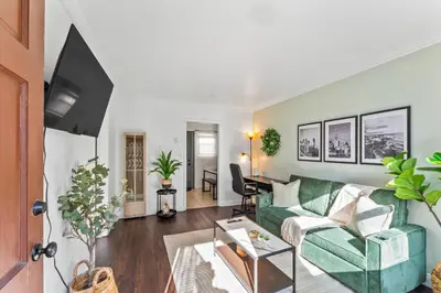 a living room with a green couch and a tv at Colorful & Cozy Oasis in North Park Walk to Restaurants, Bars, and Breweries in San Diego