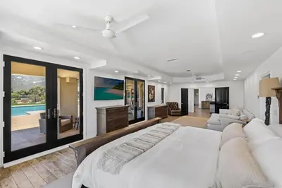 a bedroom with a large bed and a living room at Private Gated 6BR Luxury Estate, Gym, Lake View in Escondido