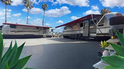 two rvs parked in a parking lot with palm trees at Retro Star-Wagon, Ocean View at Studios in Oceanside