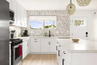 a white kitchen with white cabinets and a window at Sunny Coastal Escape Large 3BR Home Sleeps 8 in San Diego