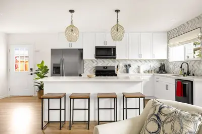 a kitchen with white cabinets and a bar with stools at Sunny Coastal Escape Large 3BR Home Sleeps 8 in San Diego