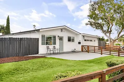 a white house with a fence and a yard at Sunny Coastal Escape Large 3BR Home Sleeps 8 in San Diego