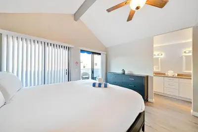 a bedroom with a large white bed and a ceiling fan at Perfect Newport Beach Location With Balcony Spa II in Newport Beach