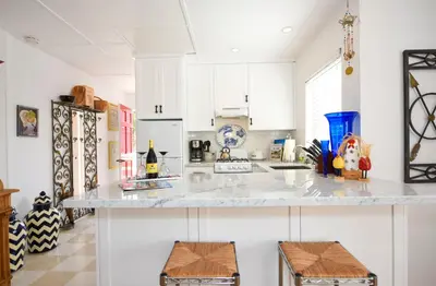 a kitchen with white cabinets and a counter with two stools at Charming Garden Cottage with Full Kitchen Walk to La Jolla Village & Beaches in San Diego