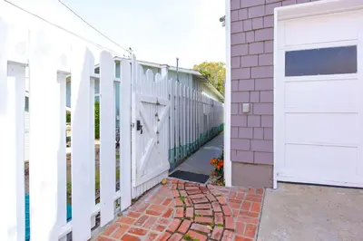 a white fence next to a house with a door at Charming Garden Cottage with Full Kitchen Walk to La Jolla Village & Beaches in San Diego