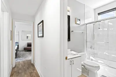 a white bathroom with a shower and a toilet at 4 Car Parking Steps 2 Lido Village Marina Phenomenal Location in Newport Beach