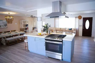 a kitchen with a stove and a living room at Coastal Chill San Diego - Heated Pool - XXL Spa - Mini Golf - Gourmet Kitchen in San Diego