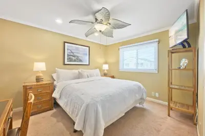 a bedroom with a white bed and a ceiling fan at Bay Breeze in Newport Beach