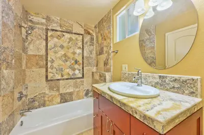 a bathroom with a sink and a tub and a mirror at Bay Breeze in Newport Beach