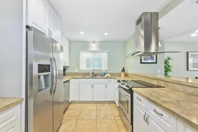 a kitchen with white cabinets and a stainless steel refrigerator at Salt & Sand I in Newport Beach