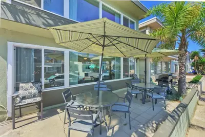 a patio with tables and chairs and an umbrella at Salt & Sand I in Newport Beach