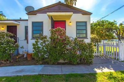 a white house with a red door and a fence at Sweet n Cozy Cottage near Little Italy & Gaslamp in San Diego
