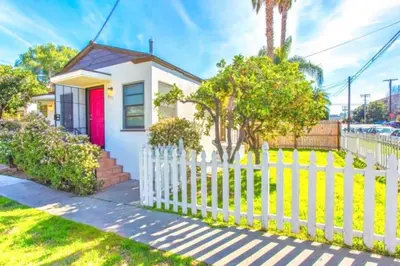 a white fence in front of a house with a red door at Sweet n Cozy Cottage near Little Italy & Gaslamp in San Diego