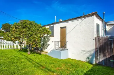 a white house with a door and a yard at Sweet n Cozy Cottage near Little Italy & Gaslamp in San Diego