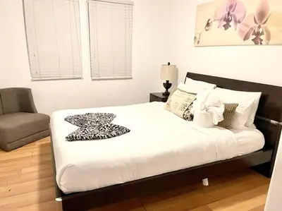 a bedroom with a large white bed with a chair at Cozy Urban Cottage in San Diego