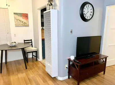 a living room with a tv and a table and a clock at Cozy Urban Cottage in San Diego