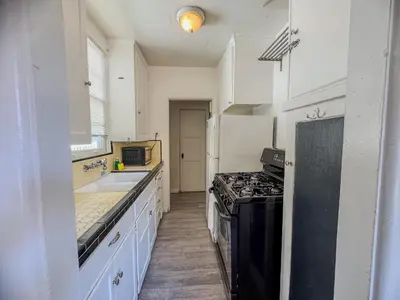 a kitchen with white cabinets and a black stove top oven at Amazing Cottage - near Little Italy Gaslamp in San Diego