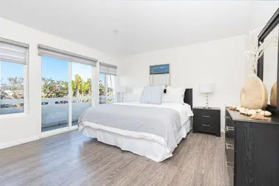 a white bedroom with a large bed and large windows at Luxury 4Br W Ac, Rooftop Deck, And Stunning Ocean Views By Beachview Rentals in Newport Beach