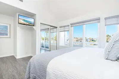 a white bedroom with a large bed and windows at Luxury 4Br W Ac, Rooftop Deck, And Stunning Ocean Views By Beachview Rentals in Newport Beach