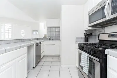 a kitchen with white cabinets and a stove at Luxury 4Br W Ac, Rooftop Deck, And Stunning Ocean Views By Beachview Rentals in Newport Beach