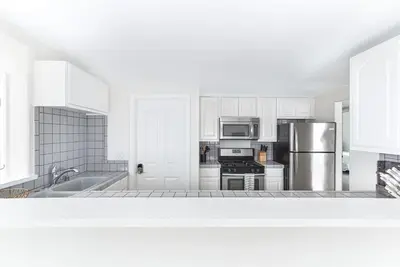 a kitchen with white cabinets and a stainless steel refrigerator at Luxury 4Br W Ac, Rooftop Deck, And Stunning Ocean Views By Beachview Rentals in Newport Beach