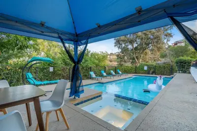 a swimming pool with a blue umbrella and chairs at Entire Private Home with 4 Bedrooms 3 Bathrooms, Big Yard, View, , King Bed, 10 Parking, Available Now in El Cajon