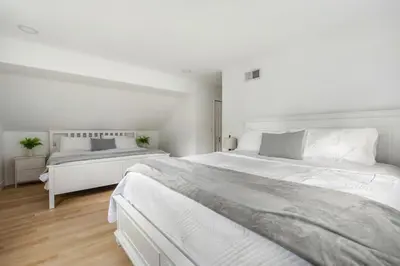 two beds in a bedroom with white walls and wood floors at Lux MV Home Live Like A Local Backyard Oasis in Mission Viejo