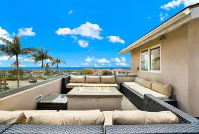 a patio with couches and a table on a balcony at Oceanview Oasis with Roofdeck Hot Tub in Carlsbad