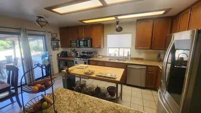 a kitchen with wooden cabinets and a stainless steel refrigerator at Temecula Wine Country Ranch with 200 year old oaks in Temecula