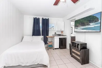 a bedroom with a bed and a kitchen with a tv at 4Br Retreat One House From The Beach And Boardwalk By Beachview Rentals in Newport Beach